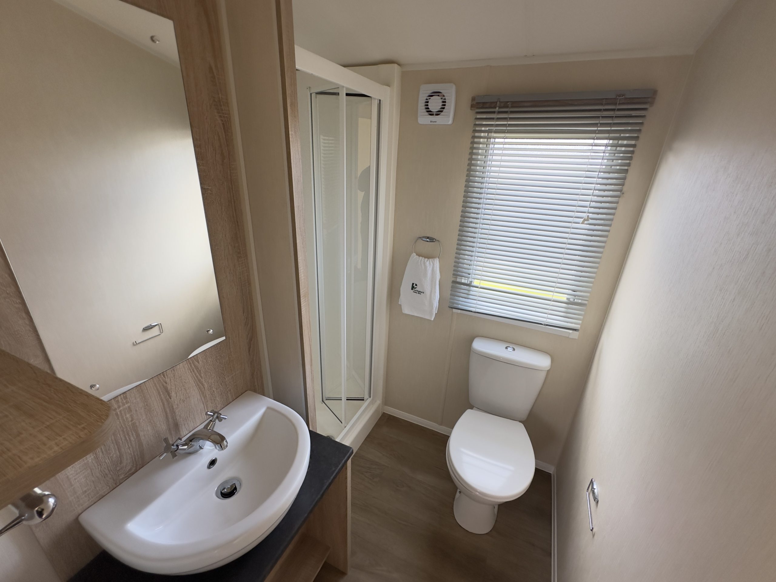 Family bathroom with sink, toilet and fitted shower unit in the Willerby Mistral 2021 caravan at Windy Harbour Holiday Park