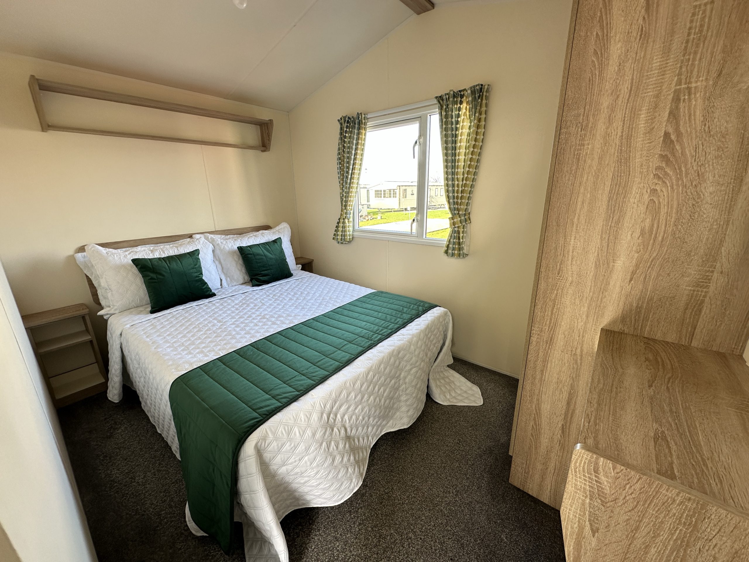 Master bedroom with double bed and overhead shelving in the Willerby Mistral 2021 caravan at Windy Harbour Holiday Park