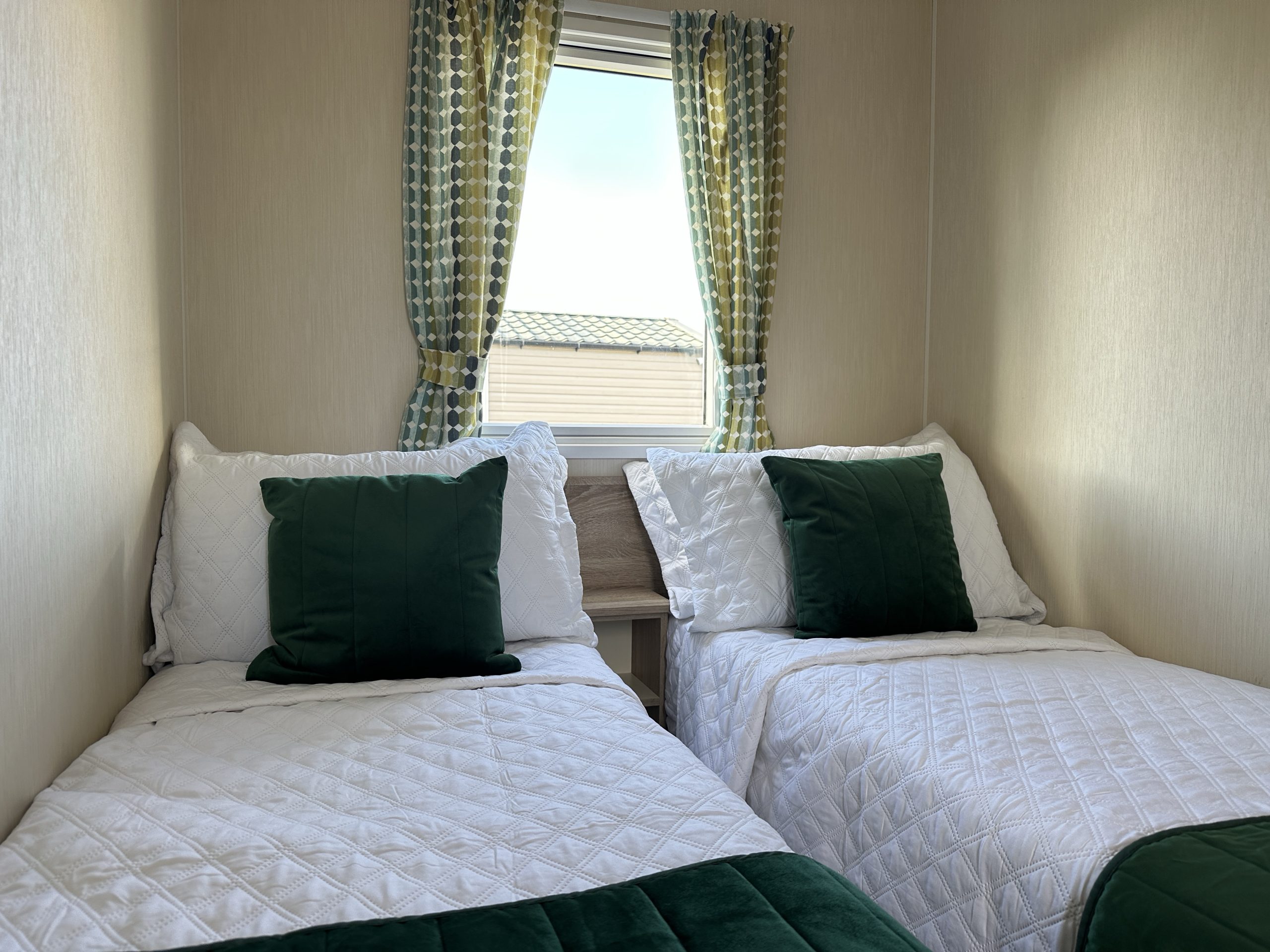 Twin bedroom with two single beds and window in the Willerby Mistral 2021 caravan at Windy Harbour Holiday Park